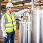 male worker in hi-vis checking the balance of the hydrogen tanks