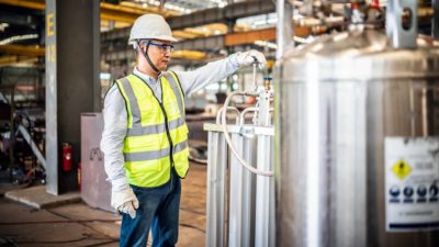 male worker in hi-vis checking the balance of the hydrogen tanks