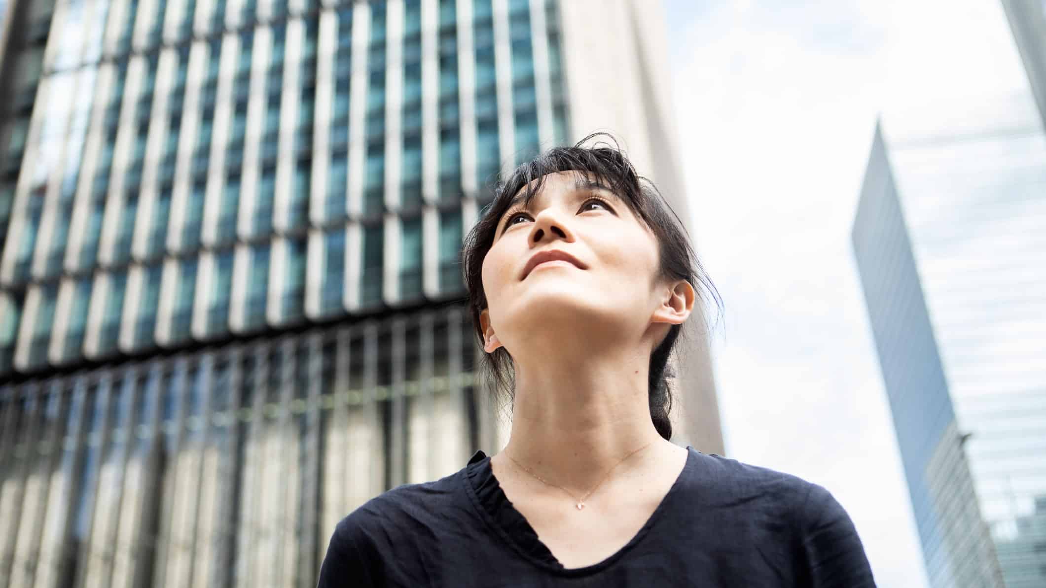 An Asian woman looks towards the sky and the future.