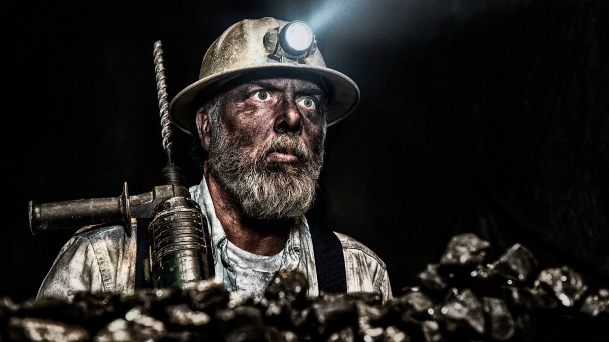 Miner with a light in the darkness as he moves coal