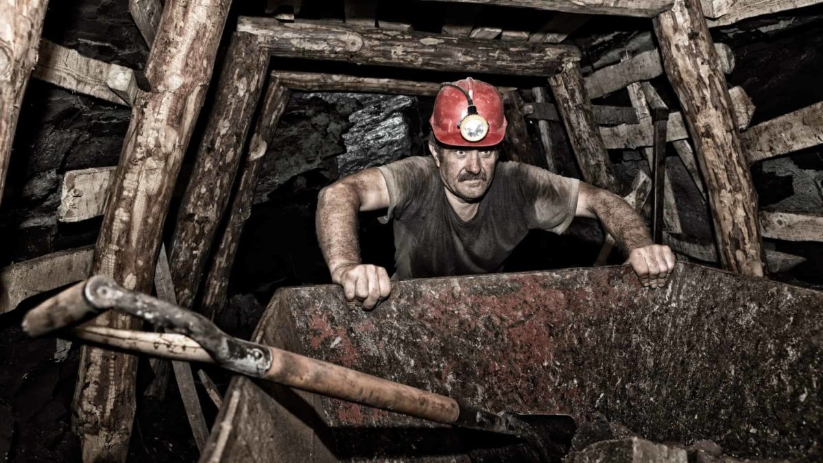 Coal Miner in the tunnels pushing a cart with tools