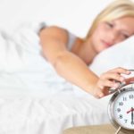Woman in bed rolls over to hit clock