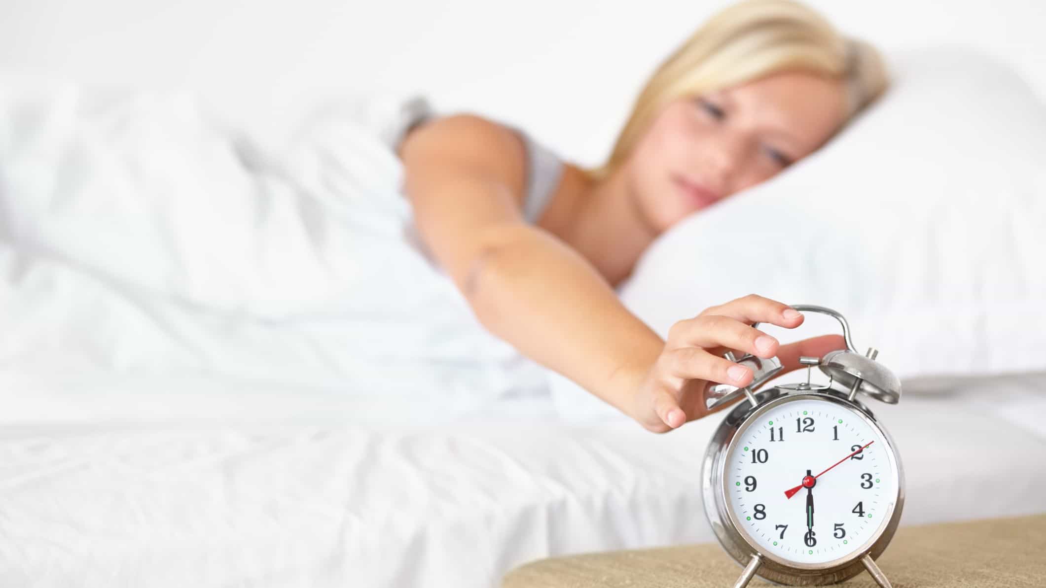Woman in bed rolls over to hit clock