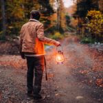 A man faces a fork in the path in the bush before being plunged into the night's darkness holding only a gas lantern.