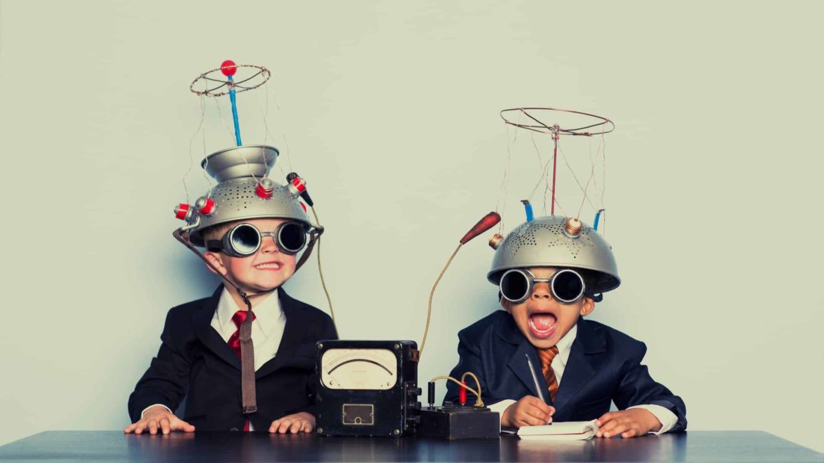 two little boys playing with helmets dressed up in suits