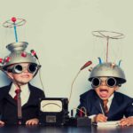 Two little boys playing with helmets dressed up in suits.
