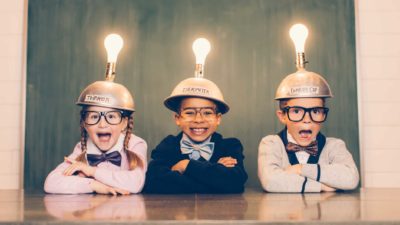 Three young nerds dressed in suits with thinking caps and lightbulbs