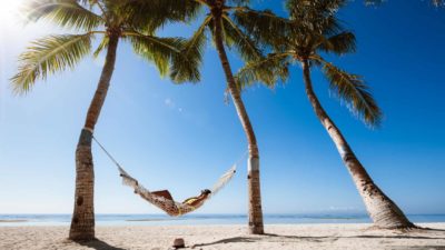 Traveller in hammock relaxing on the beach.