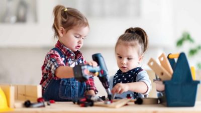 Two little girls drilling as they work on a play project.