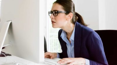 A businesswoman stares in shock at her computer screen.