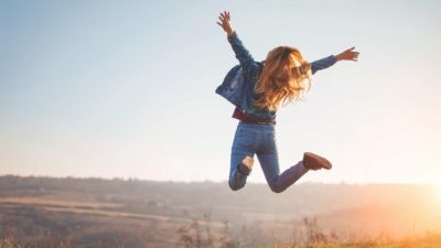 Woman jumping for joy at great news with wide open country around her.