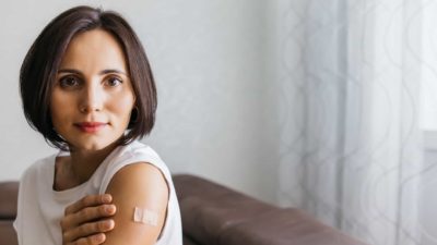 A woman has just received the COVID vaccine, showing the bandage on her upper arm.