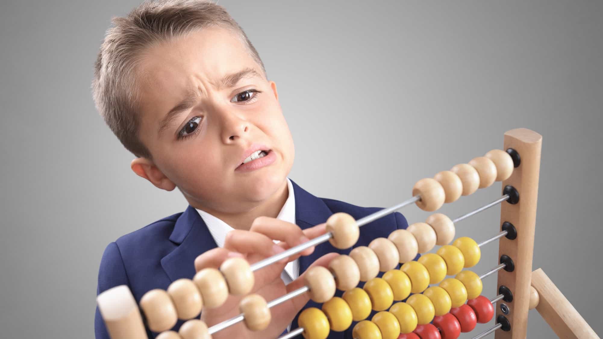 Boy looks confused as he adds up on an abacus