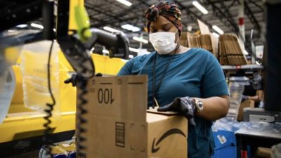 An amazon worker packaging up a delivery in a factory