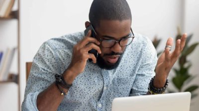 Douugh investor looking angry while talking on phone and looking at computer