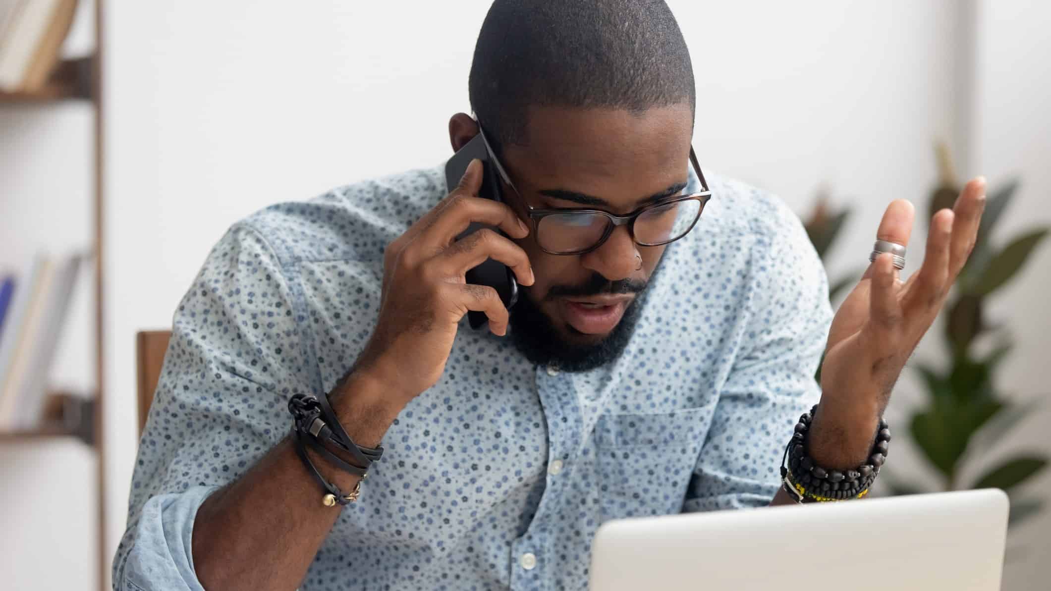 Douugh investor looking angry while talking on phone and looking at computer