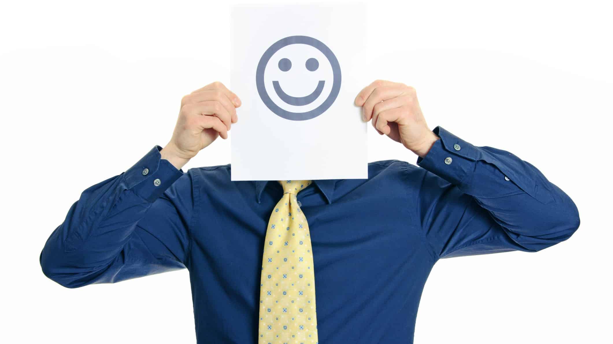 Business man holding a sheet of paper printed with a smily face in front of his own face
