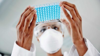 Lab technician in lab with a tray of specimens