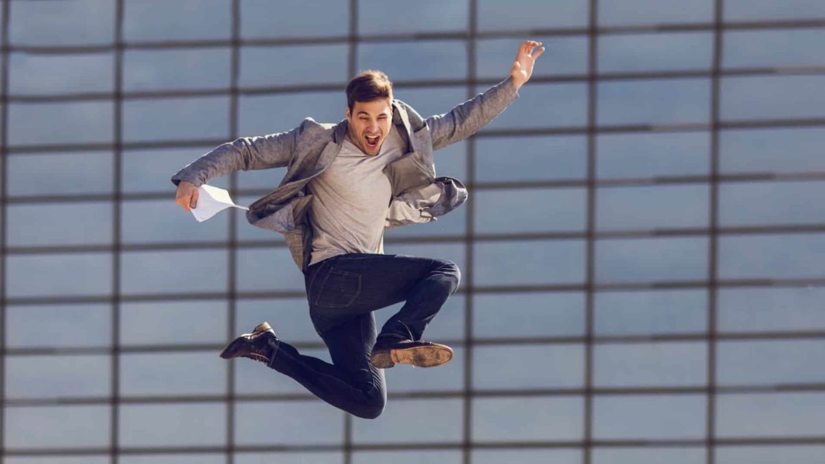 A businessman leaps in the air outside a city building in the CBD.