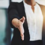 Businesswoman holds hand out to shake.