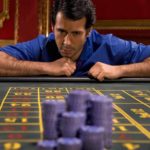 A gambler at a casino bets a pile of chips on one number.