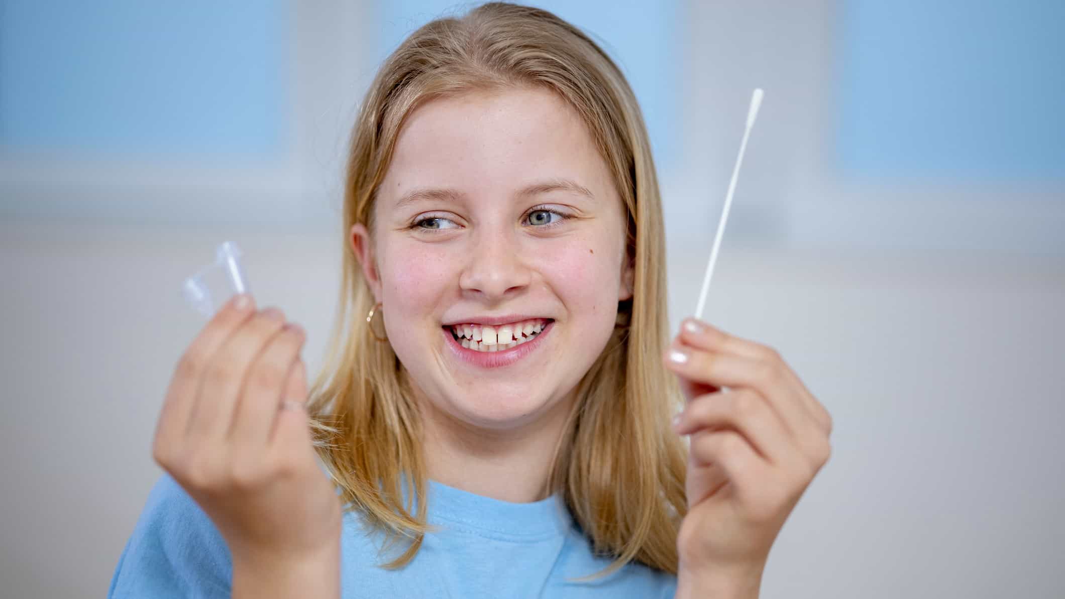 child holds swab and testing cup