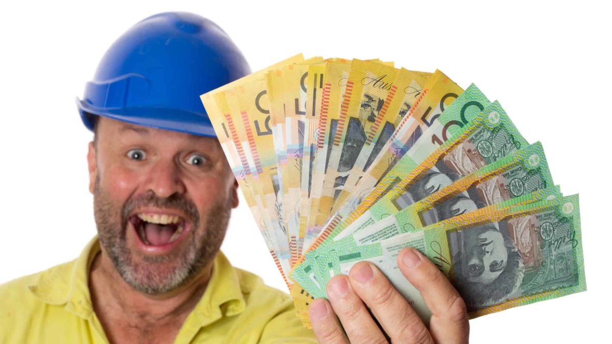 A happy construction worker or miner holds a fistfull of Australian money, indicating a dividends windfall