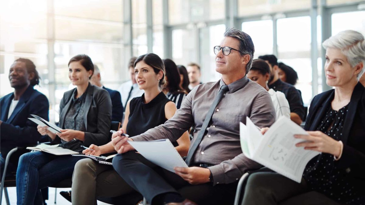 A group of business people in a board room hear the latest company report