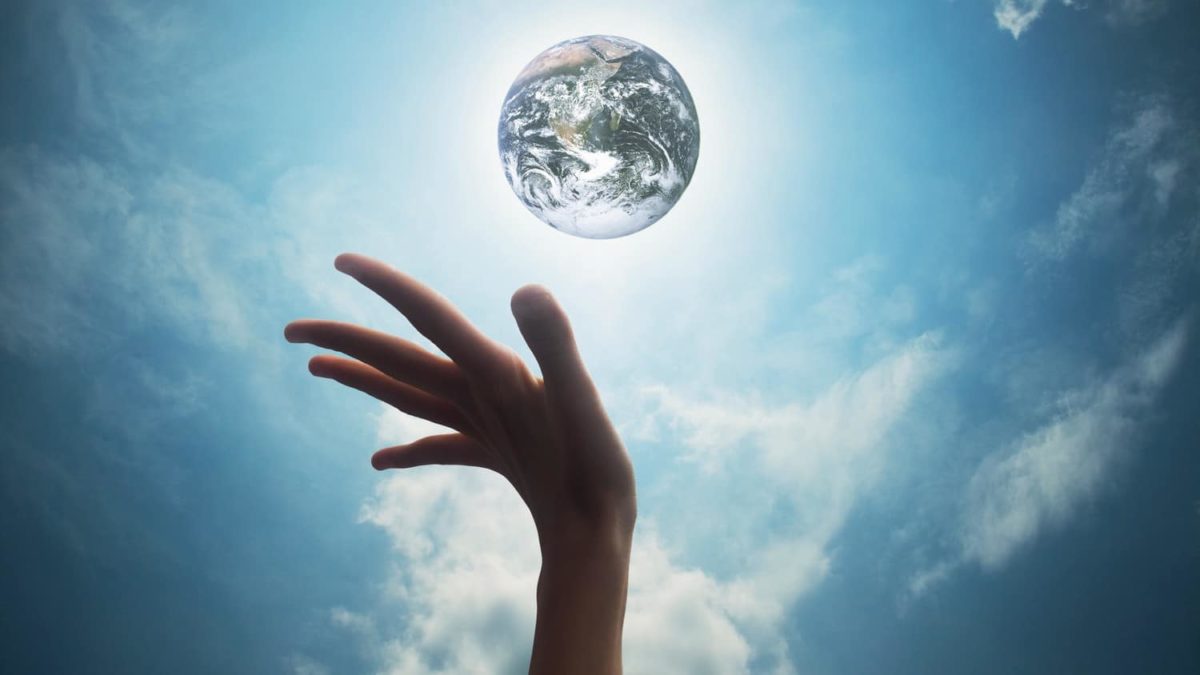 The planet earth floats in light about an outstrecthed hand, indicating sustainability