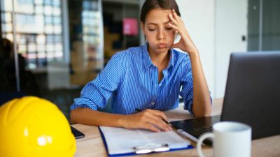 Female worker sitting desk with head in hand and looking fed up