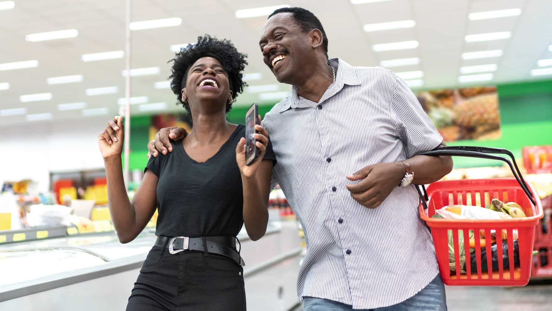 Happy couple laughing while shopping in supermarket