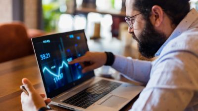 Man sits at computer and analyses stock graphic