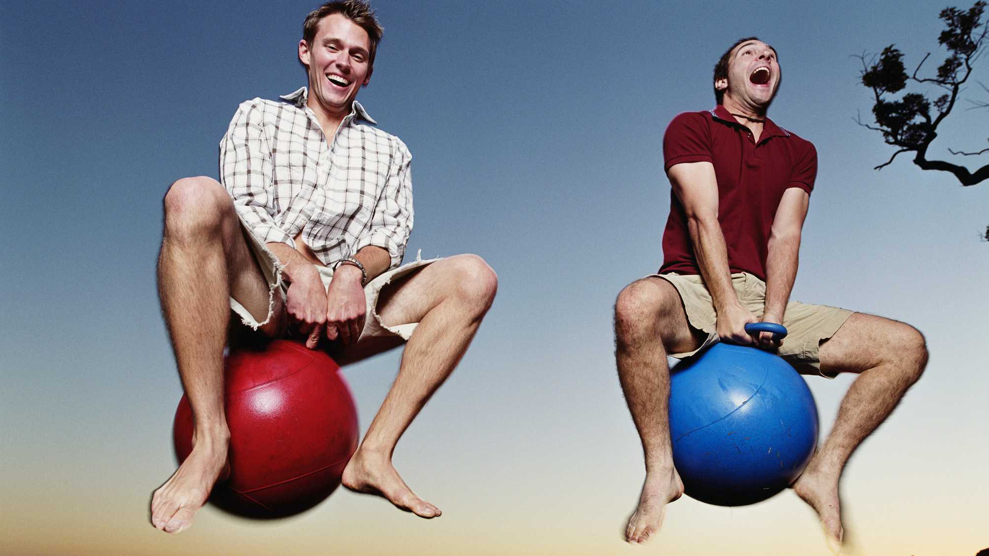 Two men laughing while bouncing on bouncy balls