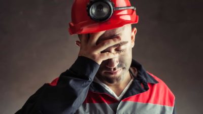 A sad Carnaby Resources miner holds his head in his hands