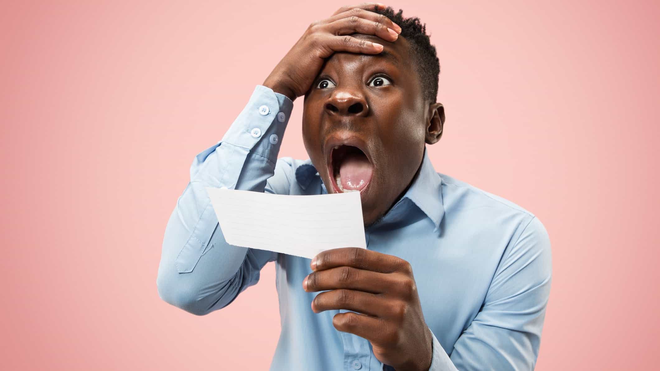 Man open mouthed looking shocked while holding betting slip