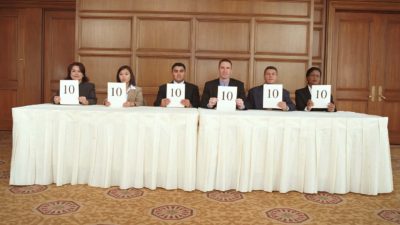 An old-fashioned panel of judges each holding a card with the number 10