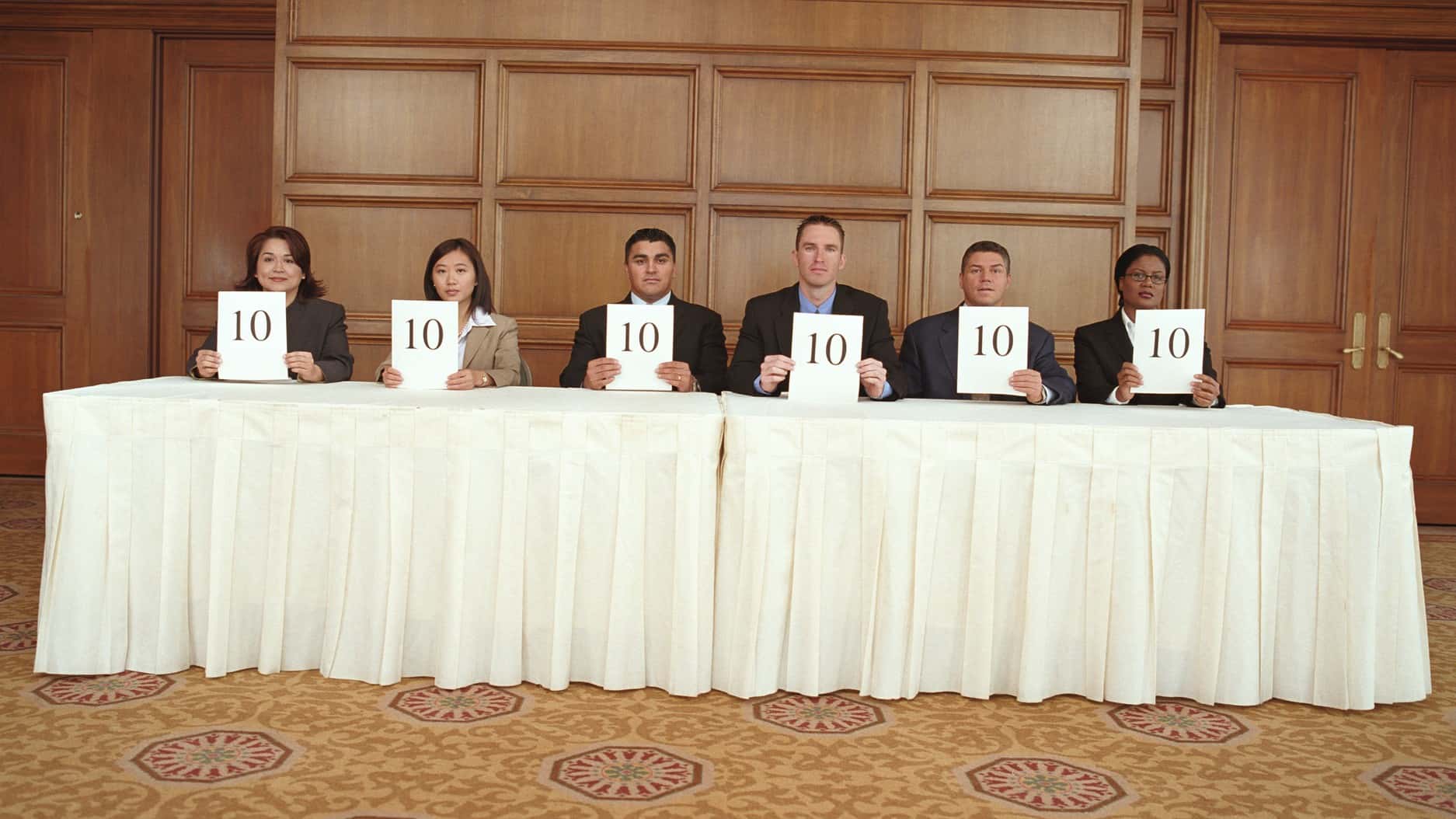 An old-fashioned panel of judges each holding a card with the number 10
