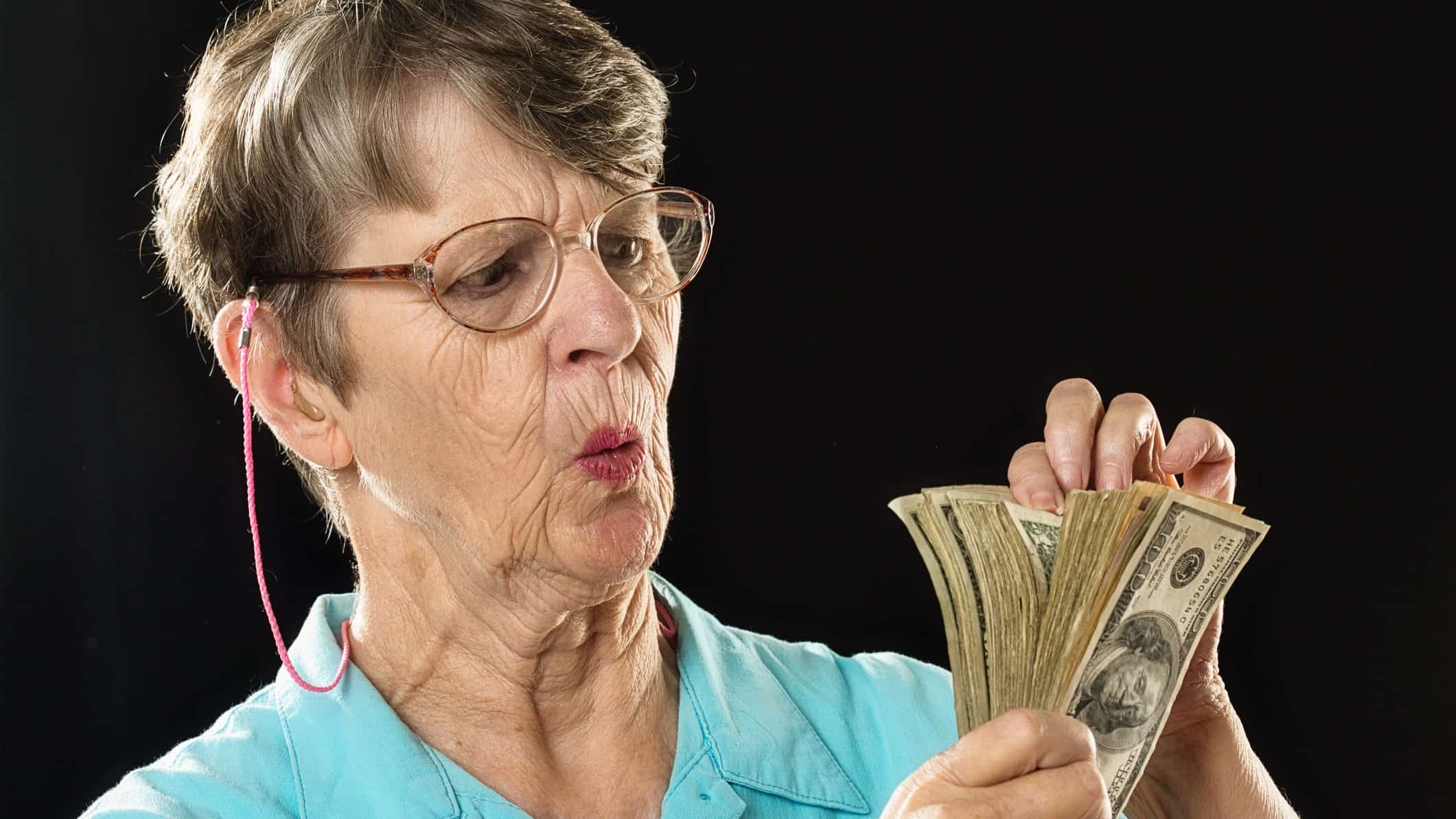 Older woman looks concerned as she counts cash notes