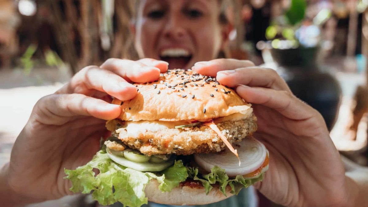 woman holding out vegan burger about to eat