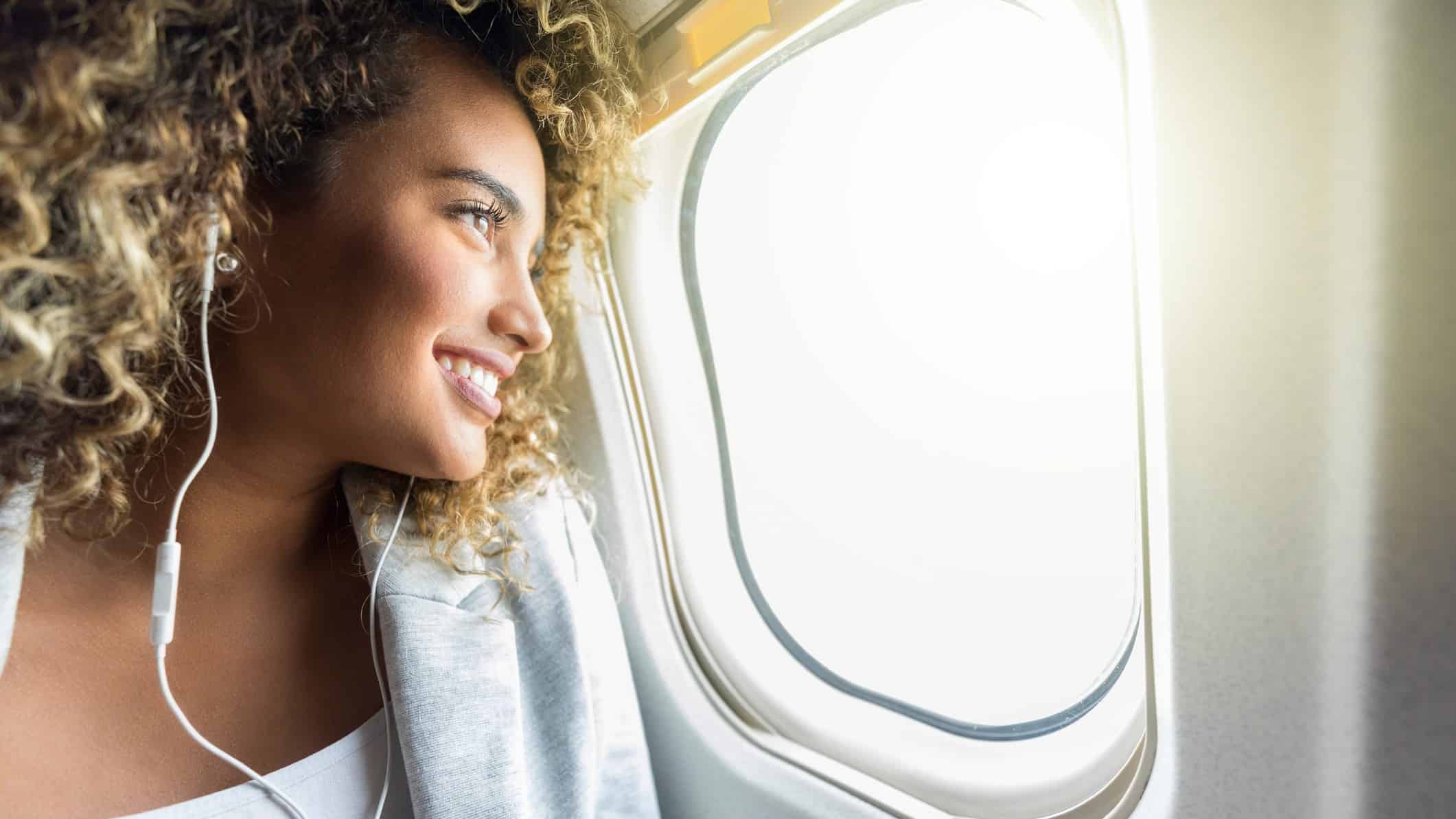 A woman smiles as she looks out an aeroplane window.