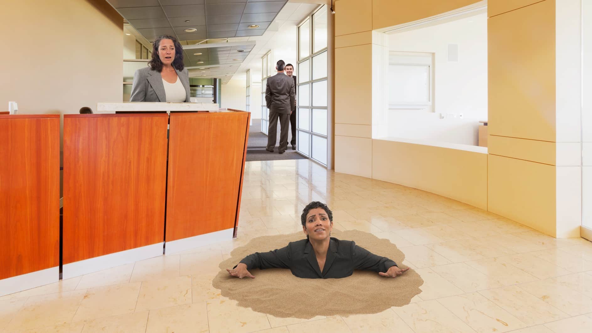 Woman in office sinking in quicksand into the floor