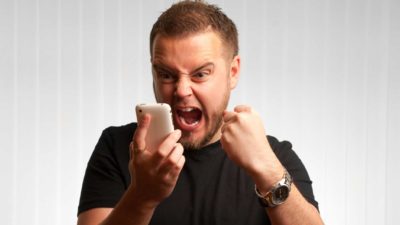 Man shouts at mobile phone with a closed fist