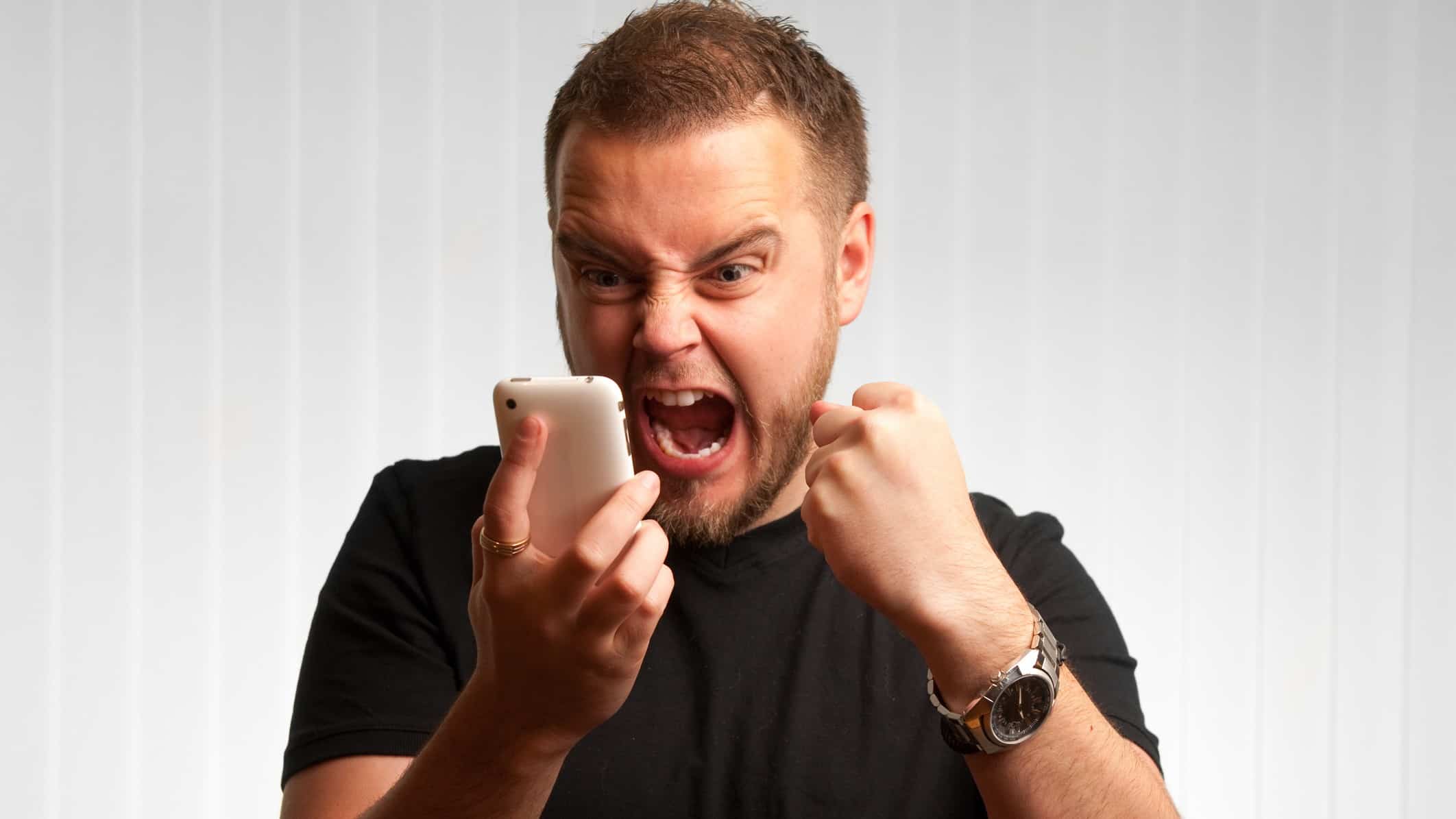 Man shouts at mobile phone with a closed fist