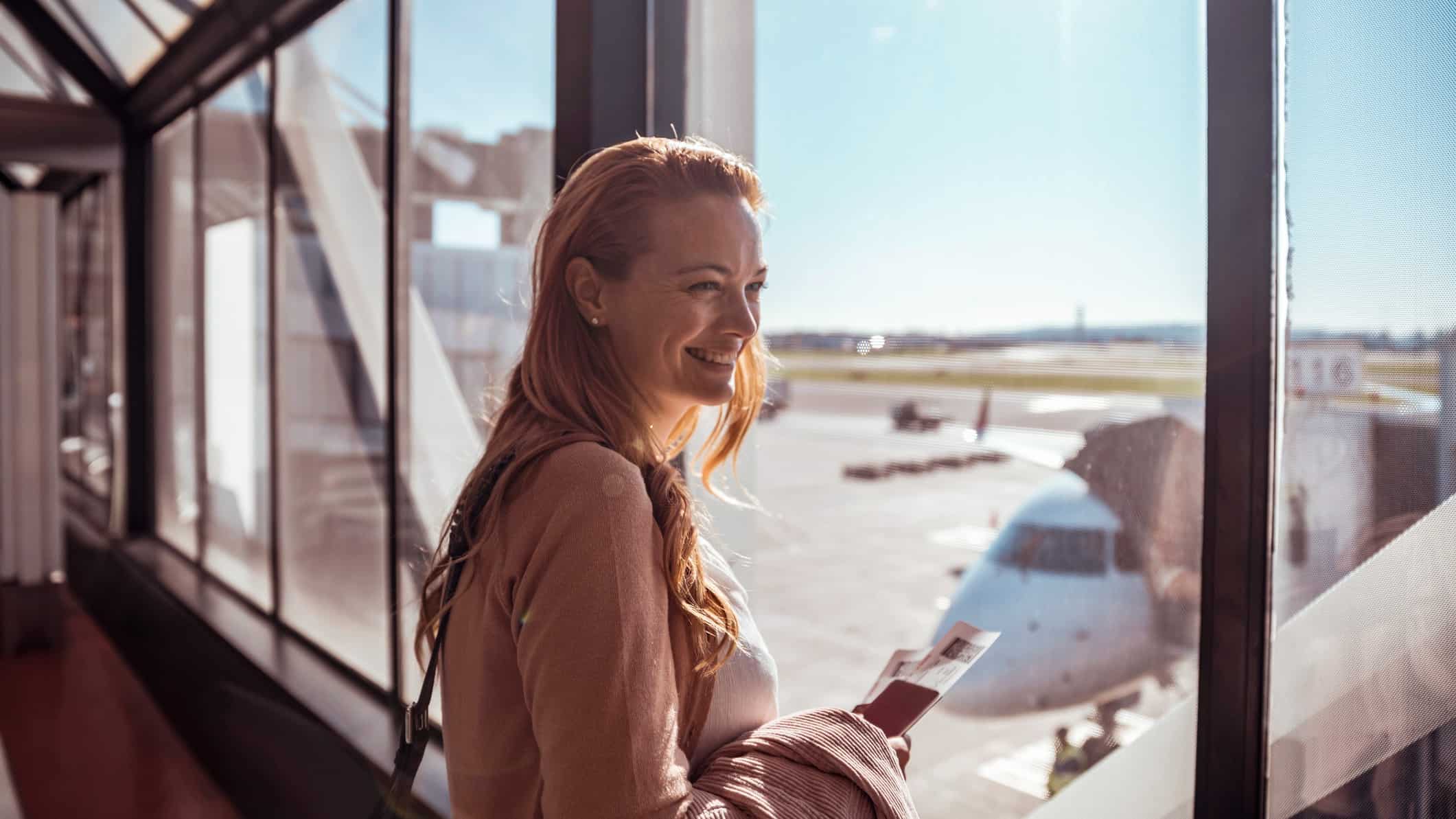 A female traveller stands in the terminal, ready to board her plane.