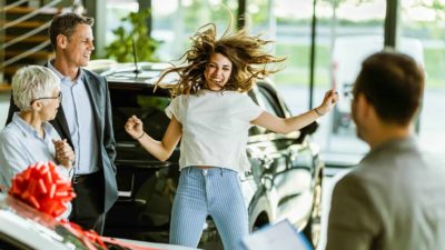 A woman leaps in the air, so excited because she just purchase a new car.
