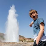 A boy is wowed at a surge of water from a blowhole.