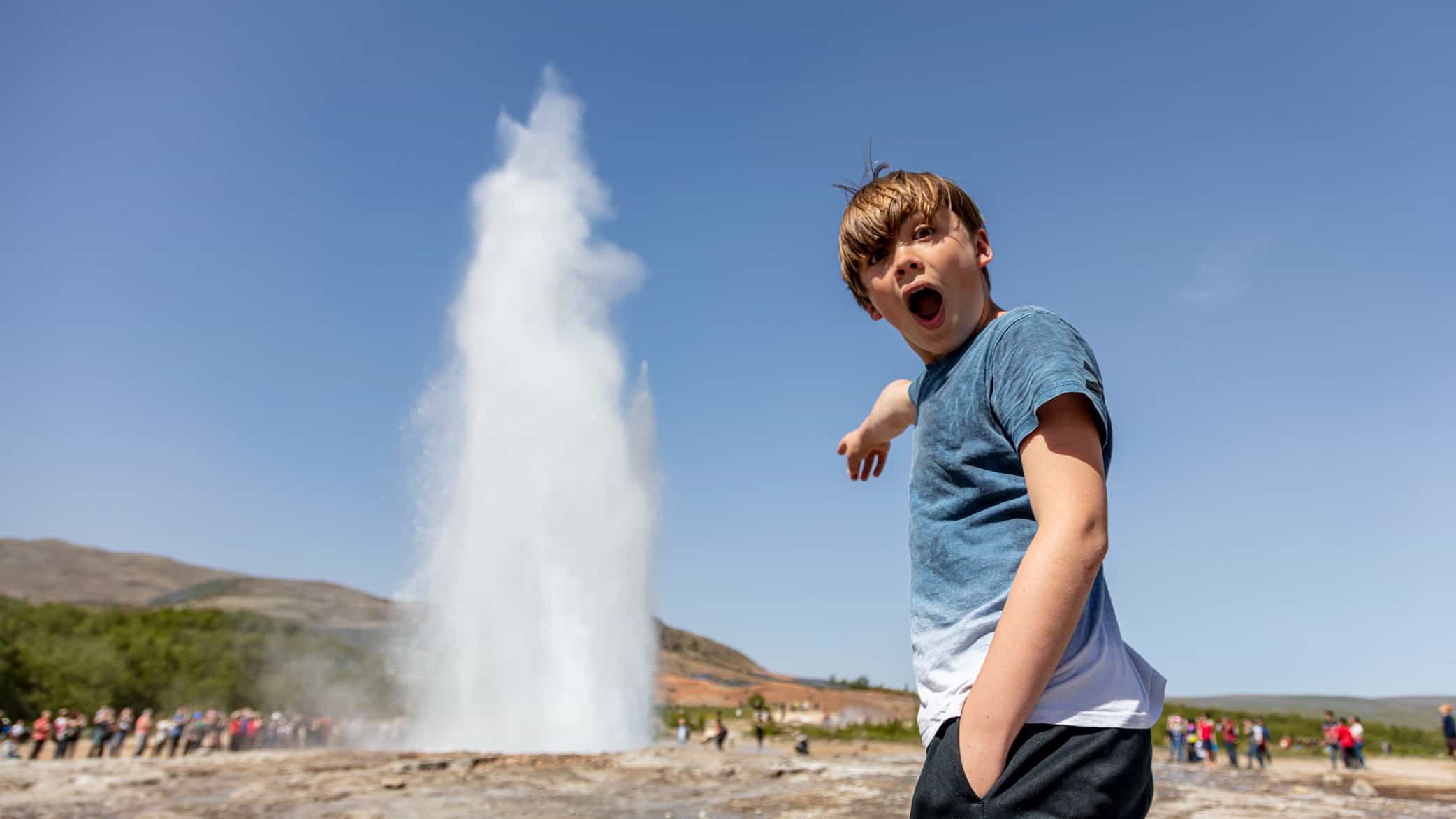 A boy is wowed at a surge of water from a blowhole.