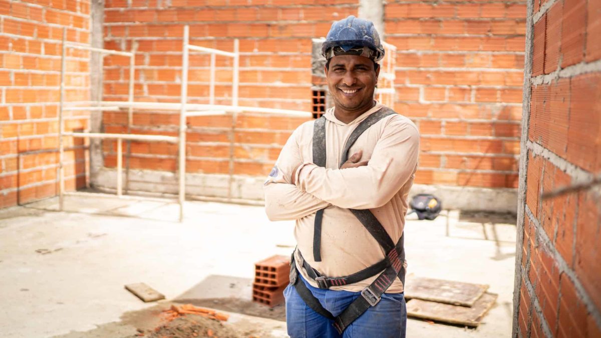 A man stands in a building site featuring brick walls with building equipment in the background.
