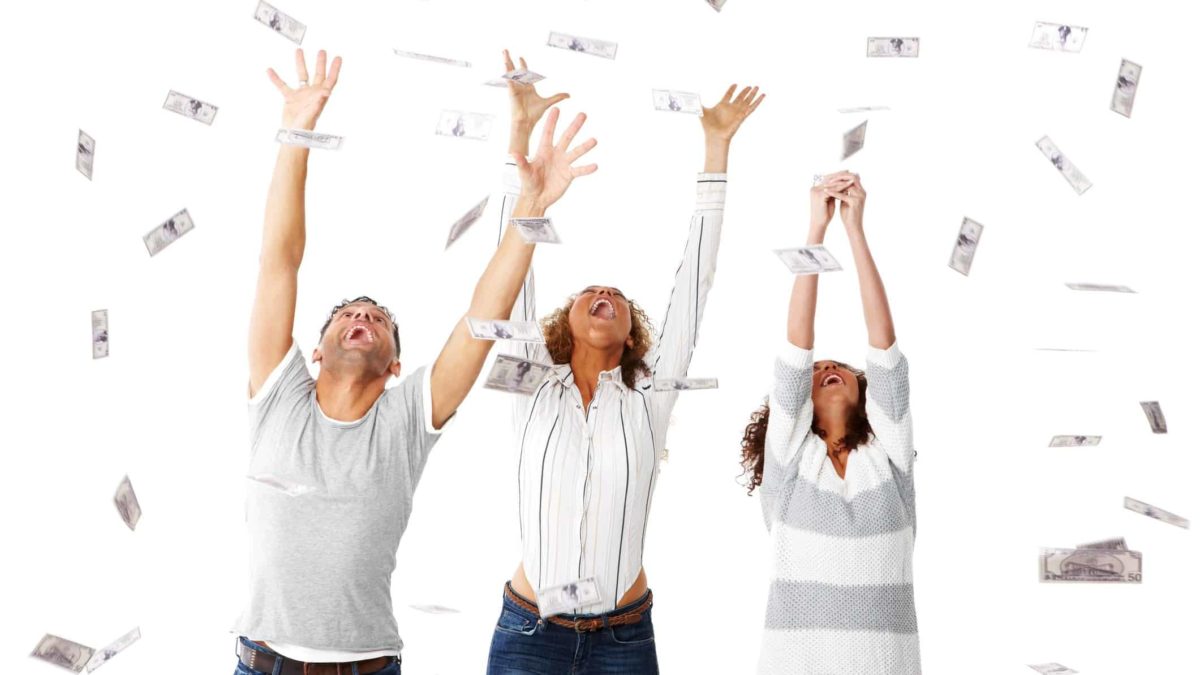 Three people raise their arms to catch banknotes swirling through the air.