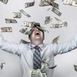 A man throws his arms up in happy celebration as a shower of money rains down on him.